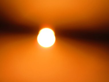 Güneşin parlak görüntüsü kahverengi gökyüzünü aydınlatıyor, sakin bir atmosfer manzarası yaratıyor..