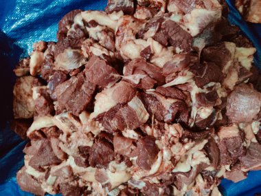 Mavi bir yüzeye dizilmiş taze çiğ et parçalarının yakından görüntüsü, dokularını ve renklerini vurguluyor. Resim aşçılık hazırlıklarını betimliyor ve gıda sunumuna odaklanmayı vurguluyor.