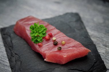 Siyah taşlı arka planda çiğ ton balığı filetosu.