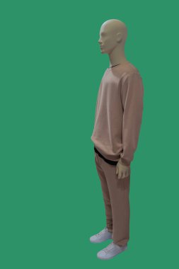 Spor kıyafet giyen bir erkek vitrin mankeni tam boy görüntüsü. Yeşil arkaplanda izole.