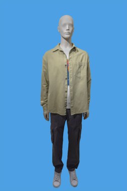 Full length image of a male display mannequin wearing open khaki shirt and dark brown pants isolated on a blue background