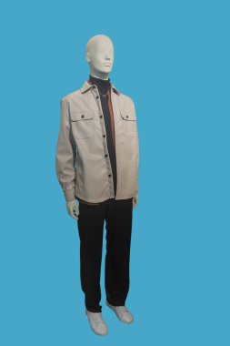 Full length image of a male display mannequin wearing beige leather jacket and black trousers isolated on a blue background