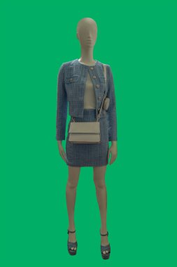 Full length image of a female display mannequin wearing fashionable gray jacket and skirt suit isolated on a green background