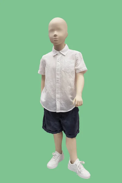 子供のディスプレイマネキンの完全な長さの画像は 緑色の背景に白いシャツと青のショートパンツを身に着けています — ストック写真