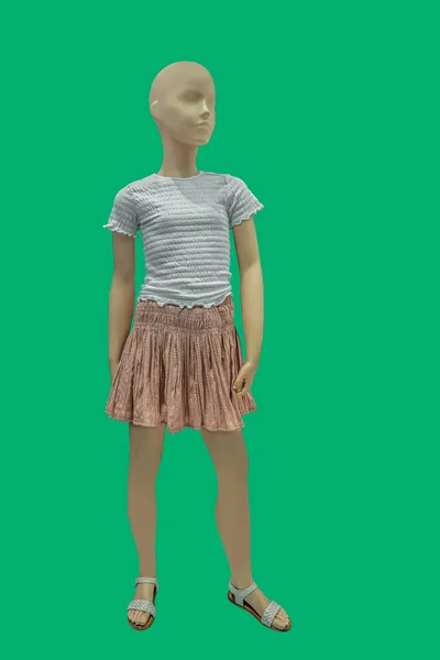 白い半袖のブラウスと緑の背景に隔離された茶色のプリーツスカートを身に着けている子供ディスプレイマネキンの完全な長さの画像 — ストック写真