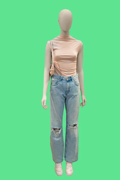 女性のディスプレイマネキンの完全な長さの画像は 緑の背景に隔離されたノースリーブピンクのブラウスとブルーのジーンズを身に着けています — ストック写真