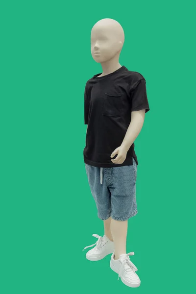 緑の背景に隔離された黒のTシャツとジーンズのショートパンツを身に着けている子供ディスプレイマネキンの完全な長さの画像 — ストック写真