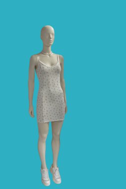 Mavi arka planda izole edilmiş omuz kayışlı, modaya uygun beyaz kolsuz bir elbise giyen bir kadının tam boy görüntüsü.