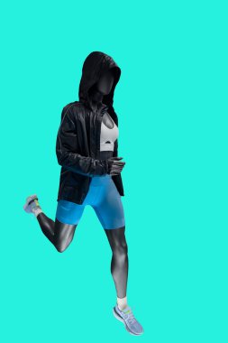 Yeşil arka planda izole edilmiş modaya uygun spor giyimli, çalışan bir kadın vitrin mankeninin tam boy resmi