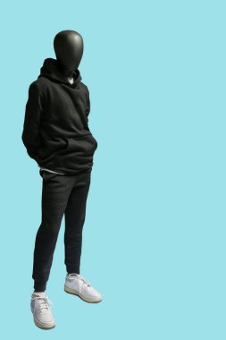 Mavi arka planda izole edilmiş siyah spor takım giyen bir erkek vitrin mankeni.