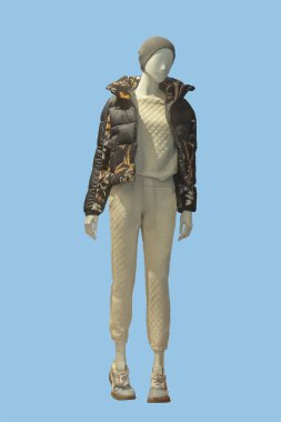 Mavi arka planda kahverengi fermuarsız ceket, bluz ve pantolon giyen bir kadın vitrin mankeni.