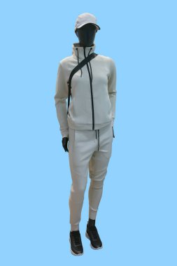 Mavi arka planda izole edilmiş beyaz spor takım elbiseli bir kadın vitrin mankeni.