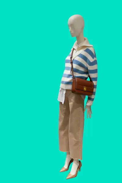 stock image Full length image of a female display mannequin wearing stripe sweatshirt topped with a zip neckline and light brown trousers isolated on green background isolated on green background