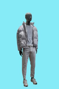 Beyaz pantolon giyen ve mavi arka planda izole edilmiş, fermuarsız ceketli bir erkek vitrin mankeni.