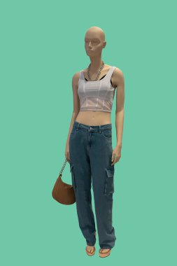 Yeşil arka planda izole edilmiş beyaz bluz ve mavi kot giyen bir kadın vitrin mankeninin tam boy görüntüsü.
