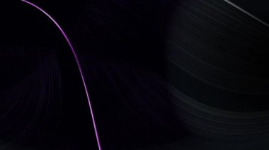 Neon mor ve yeşil iplikler koyu bir arka planın etrafında süzülüyorlar.