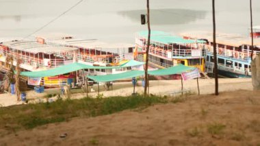 Park halindeki dört feribot, deniz kıyısında çadır ve direkler.