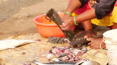 Balıkları kolayca kesmek için ayakta duran bir kılıç kullanan bir kadın.