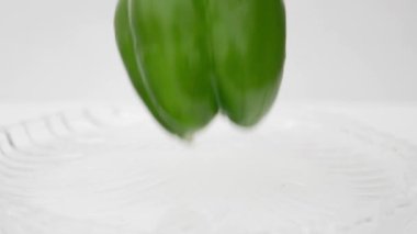 Beyaz cam levhada düşen yeşil Capsicum.