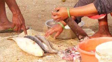 Bir balık satıcısı keskin bir kılıçla balığın keskin kenarlarını kesiyor.