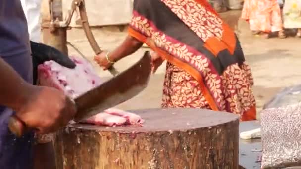 男人用弯刀把鱼切成碎片 女人则从后面取水 — 图库视频影像