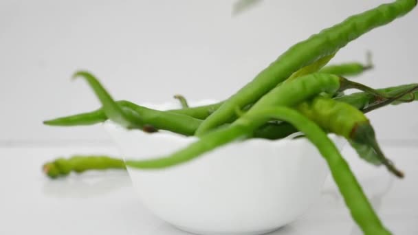 Padající Zelené Chilli Papričky Bílém Talíři — Stock video