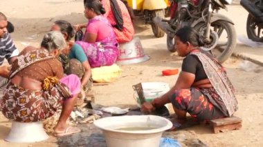 Oturan, tartışan ve balık işi yapan kadınlar, bir erkek de burada oturuyor.