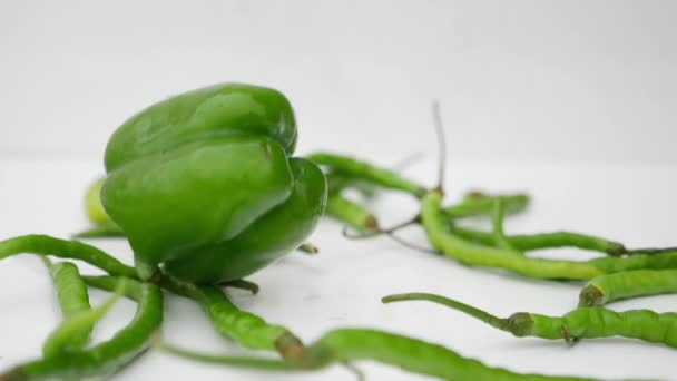 Fallende Grüne Chilischoten Und Paprika Vor Weißem Hintergrund — Stockvideo