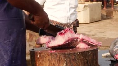 Bir adam balığın içini temizler ve alıcı için balığı küçük parçalara ayırır.