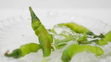 Beyaz su tabaklarında düşen yeşil biberler