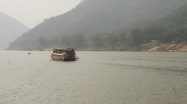 Denizde hareket eden bir feribotun arka manzarası, önünde bir tekne.