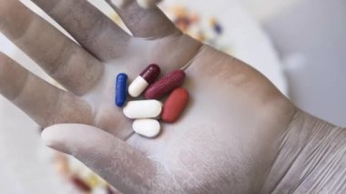 Ellerinde haplar ve kapsüller tutan eldivenler.