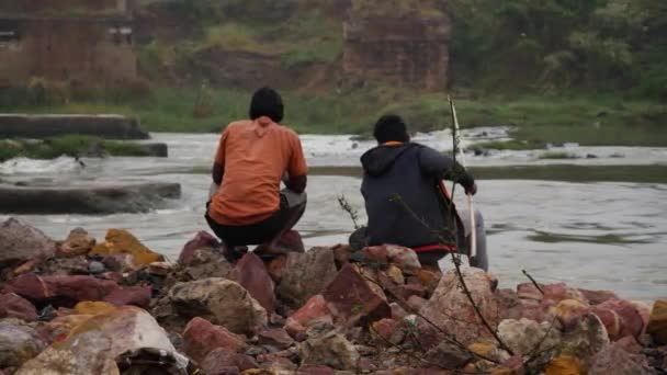 Visão Traseira Dois Homens Sentados Rochas Junto Rio Segurando Varas — Vídeo de Stock