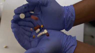 Ellerinde haplar ve kapsüller tutan eldivenler.