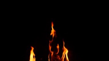 Ateş yanıyor, hafif alevler yükseliyor, siyah arkaplan