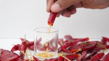 Düşen kırmızı kurutulmuş biber tohumları bardakta