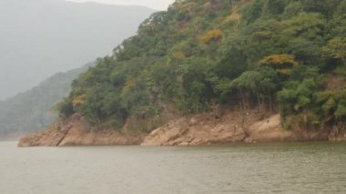 Arka taraftaki sisli dağların, çalı tepenin ve yeşil denizin uzak video klip manzarası