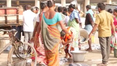 İki kadın arka planda iki büyük tavaya uzun balıklar koyuyor Chirala Balık Pazarı, AP, Hindistan - Aralık 2022