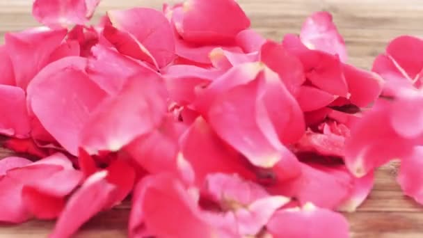 Лепестки Роз Падают Замедленной Съемке Деревянным Столом — стоковое видео