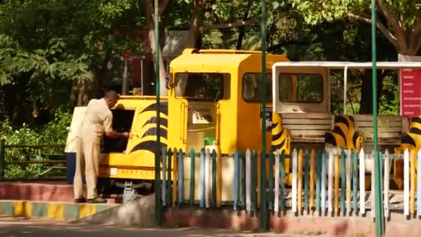 Man Working Yellow Truck While Another Man Stands Next Park — Stock Video