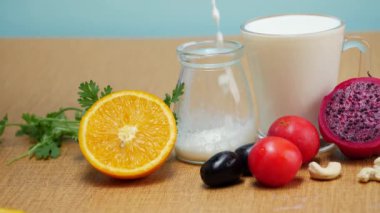 Masada bir bardak süt, domates ve portakal var. Bir şişe de süt var.
