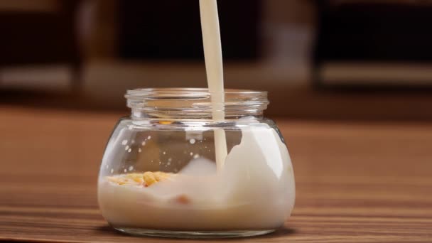 ミルクとシリアルの瓶 グラスにミルクを注ぎ ドライフルーツでヨーグルト — ストック動画