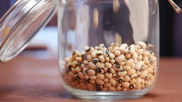 一个盛满黑眼豌豆和黑豆种子的玻璃瓶 — 图库视频影像