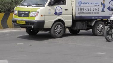 A side view of a white truck driving on a paved road and men driving on moto bikes