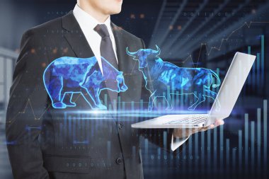 Stock exchange trading concept. The bulls and bears struggle. Equity market illustration. Close up of hand holding tablet with creative hologram and graph on blurry office interior background. Double exposure clipart