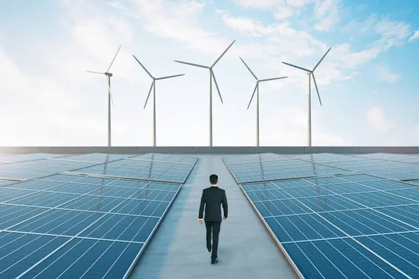明るい空に風工場とソーラーパネルを備えたグリーンエネルギーコンセプト エコエネルギーについて考えるビジネスマン — ストック写真