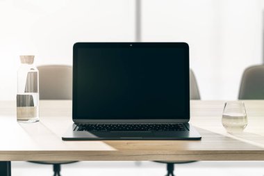 Boş, siyah, modern laptop ekranında ön manzara. Logonuz için yer var ya da ofis arka planında cam ve su şişesi olan ahşap masa üzerinde yazı var. 3B görüntüleme, düzenle