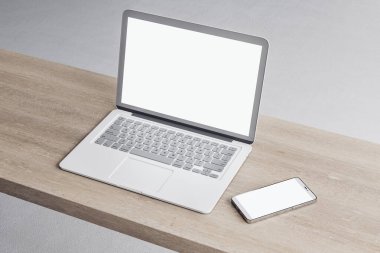 Boş beyaz dizüstü bilgisayarı ve ahşap masaüstündeki akıllı telefonu kapat. Ekrandaki yeri düzenle, beton döşeme arkaplanı. 3B Hazırlama