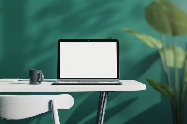 Close up of creative designer office desktop with empty white laptop screen with mock up place in frame, green wall background with sunlight and shadows, blurry decorative plant and coffee cup. 3D Rendering