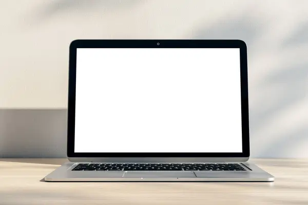 Stock image Closeup of modern laptop with blank white screen and place for your logo or text on light wooden table and sunlit wall background. 3D rendering, mock up